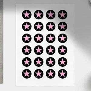 Puede incluir: Una hoja blanca con un patr&oacute;n repetitivo de estrellas rosas dentro de c&iacute;rculos negros. Las estrellas son de cinco puntas y est&aacute;n centradas en los c&iacute;rculos. El dise&ntilde;o est&aacute; espaciado uniformemente en el papel.