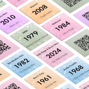 May include: A selection of colourful cards displaying song titles, artist names, and years. Each card has a unique design with decorative elements and a QR code. The cards include songs like "Single Ladies" and "Like a Virgin".