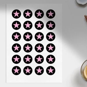 Pode incluir: Uma folha de autocolantes com estrelas cor-de-rosa dentro de c&iacute;rculos pretos. Os autocolantes est&atilde;o dispostos numa grelha sobre um fundo branco. As estrelas t&ecirc;m cinco pontas e s&atilde;o de cor rosa s&oacute;lida.