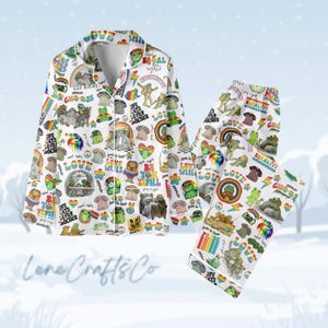 May include: White pajama set with a colorful pattern of frogs, rainbows, mushrooms, and text including "Gay Rights" and "Love Wins". The set includes a button-down shirt and matching pants.