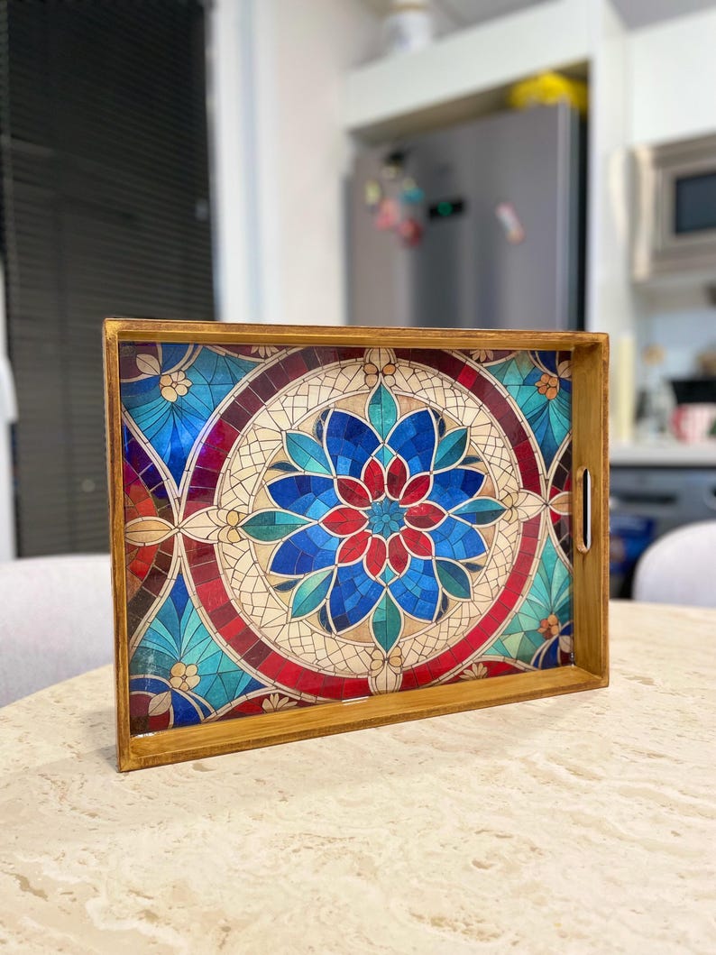 May include: A wooden serving tray with a colorful stained glass design featuring a blue, red, and green floral pattern. The tray has a brown wooden frame and a handle on the side.