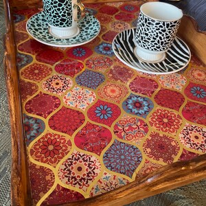 May include: A wooden tray with a colorful mosaic design featuring red, blue, and gold accents. Two ceramic cups with black and white animal print designs are placed on the tray, each with a matching saucer.
