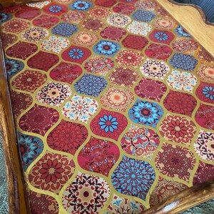 May include: A wooden serving tray with a decorative, colorful, geometric pattern. The tray has a handle and a scalloped edge.