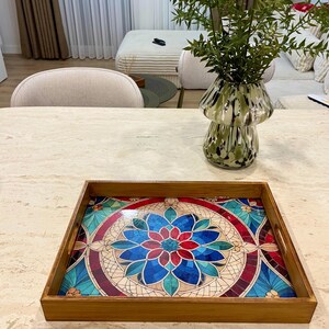 May include: A wooden serving tray with a colorful mosaic design featuring blue, red, and green tones. The tray has two handles on the sides.
