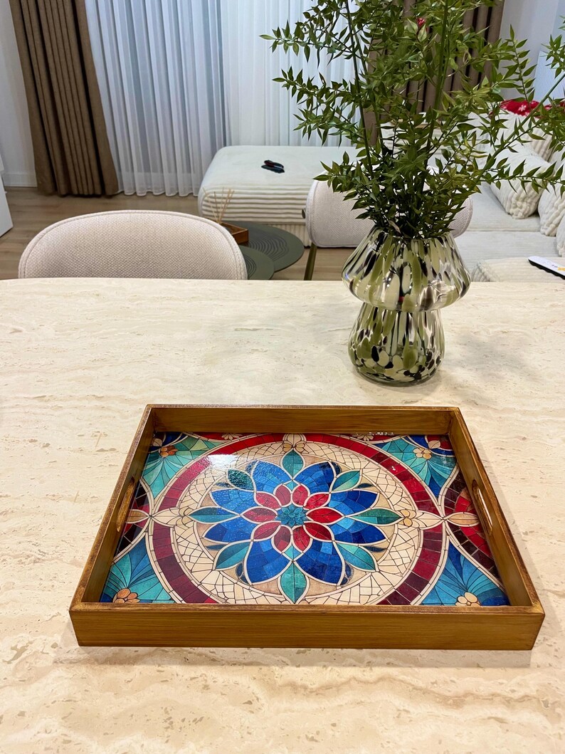 May include: A wooden serving tray with a colorful mosaic design featuring blue, red, and green tones. The tray has two handles on the sides.