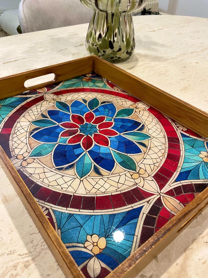 May include: A wooden serving tray with a colorful mosaic design featuring blue, red, and green tones. The mosaic design is reminiscent of stained glass.