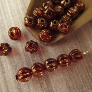 May include: A collection of small, round, copper-colored beads with a ribbed texture. Some beads are strung on a thin wire.