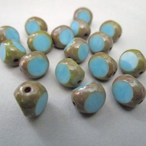 May include: A collection of artisan beads. Each bead features a light blue circle on a brown and green background. The beads have a glossy finish and a hole for stringing. Ideal for jewelry making and crafting.