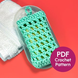 May include: A teal crocheted soap dish with a hanging loop. The soap dish is sitting on a white towel and a clear plastic dish. The image includes the text "PDF Crochet Pattern".