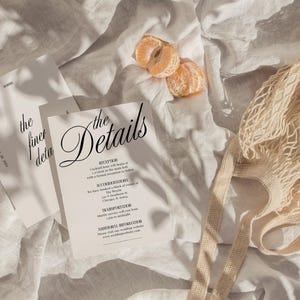 May include: Two white cards with black text on a white linen background. The text on the cards reads "the finer details" and "the Details". The second card has a list of details for a wedding reception.