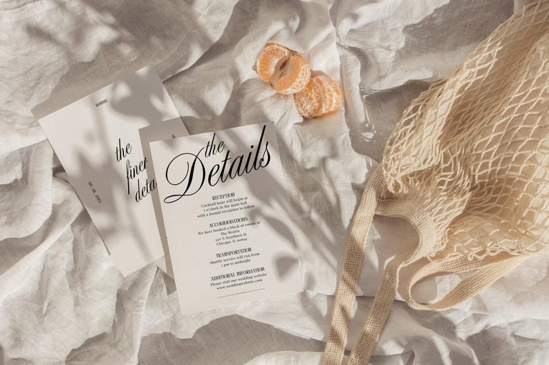 May include: Two white cards with black text on a white linen background. The text on the cards reads "the finer details" and "the Details". The second card has a list of details for a wedding reception.