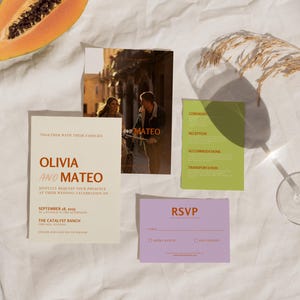 May include: Wedding invitation suite with a cream background. The main invitation features the names Olivia and Mateo in orange text. The RSVP card is purple with the text RSVP in orange. The information card is green with the text Ceremony, Reception, Accommodations, and Transportation in black text.