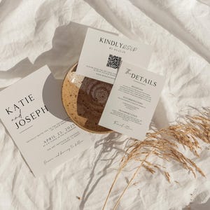May include: Wedding invitation suite with a minimalist design. The invitation card features the names "Katie and Joseph" and the date "April 23, 2023". The RSVP card has a QR code and the text "Kindly RSVP by 01.01.2023". The details card lists the ceremony and reception locations.