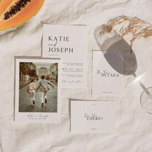 May include: Wedding invitation suite with a minimalist design. The invitation features a photo of a couple walking away from the camera. The text on the invitation reads "Katie and Joseph" and "April 23, 2023". The RSVP card reads "Save the Date?"