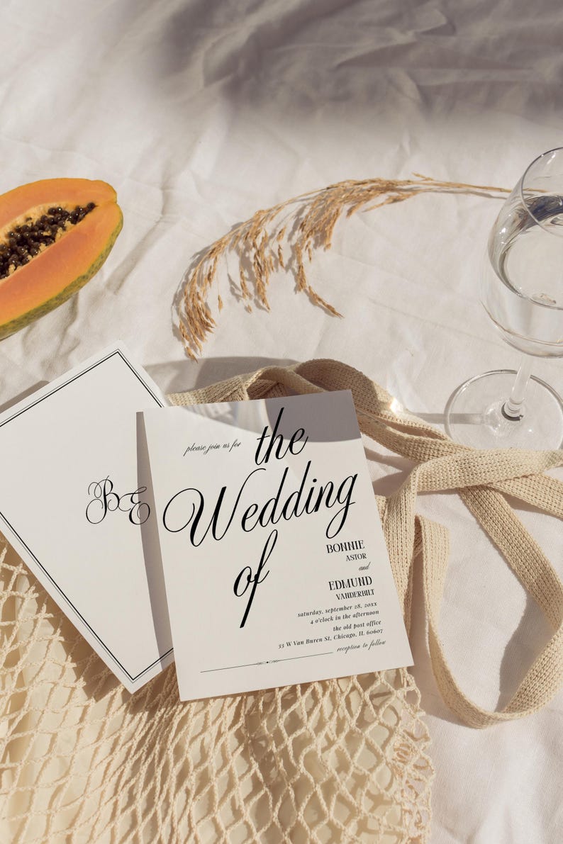 May include: A wedding invitation with a white background and black text. The invitation reads "The Wedding of Bonnie Astor and Edmund Vandererli" and includes the date and time of the wedding. The invitation is lying on a white surface with a brown woven bag and a papaya.