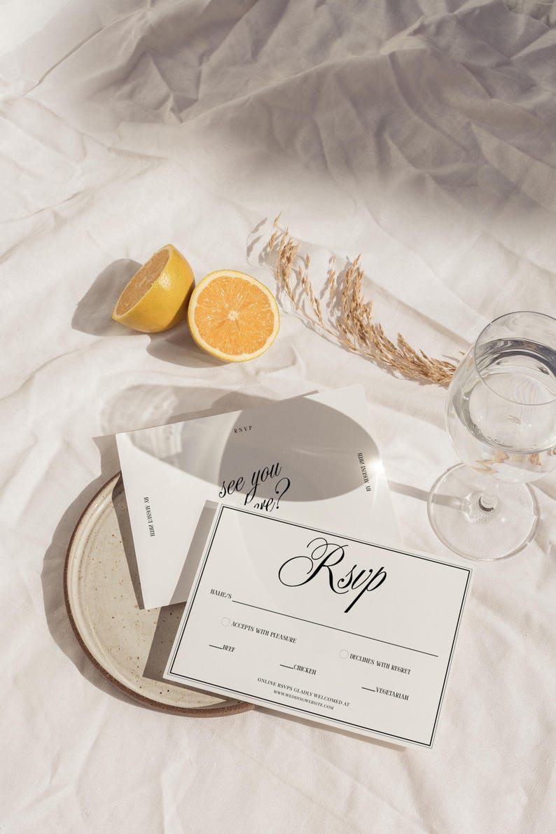 May include: A white RSVP card with black text that says "see you there?" and "RSVP". The card has a section for the guest's name, a checkbox for accepting or declining the invitation, and a choice of meal options: beef, chicken, or vegetarian.