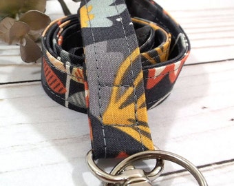 May include: A black, gray, orange, and blue patterned fabric lanyard with a silver swivel clasp.