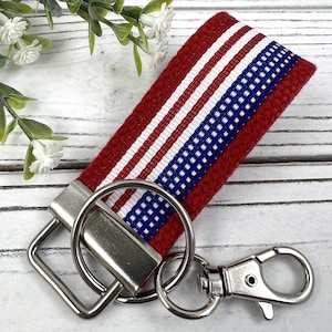 May include: Red, white, and blue striped fabric key chain with a silver key ring and a silver lobster clasp.