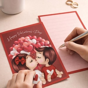 May include: Valentine's Day card with a cartoon couple kissing, surrounded by heart-shaped balloons. The card is red with the words "Happy Valentine's Day". A blank pink card and a cup of coffee are also in the image.