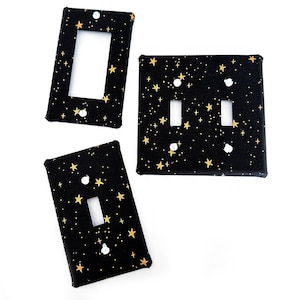May include: Three black light switch covers with gold star patterns. The covers are for single and double light switches.