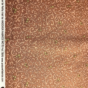 May include: A brown fabric with a repeating pattern of green leaves and brown swirls. The fabric has a vintage feel and would be perfect for quilting or crafting.