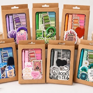 May include: Eight rectangular kraft paper boxes with clear windows, each containing a color-coordinated stationery set. The sets include pens, highlighters, sticky notes, and various book-themed stickers and accessories in purple, green, orange, blue, pink, and teal.