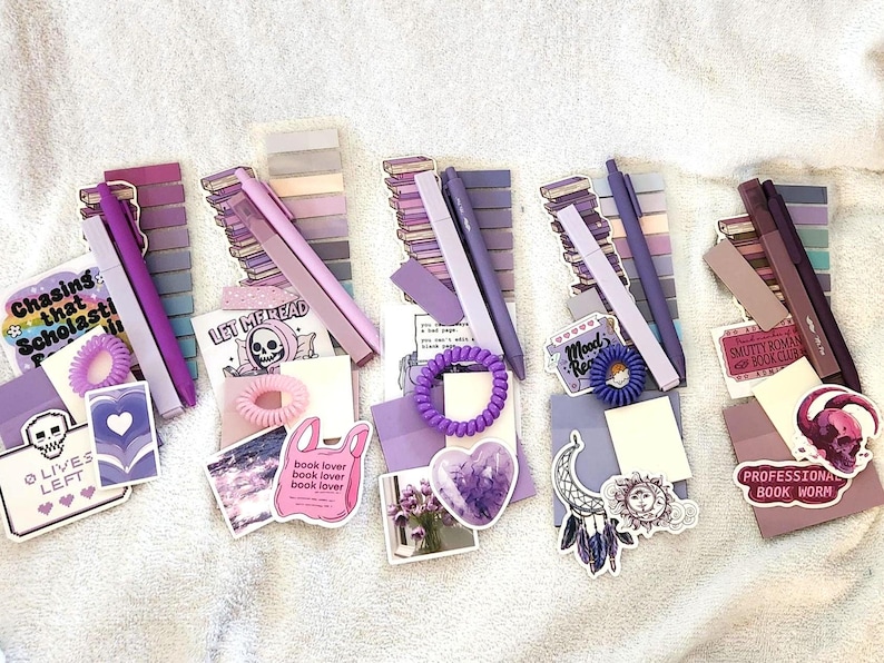Peut inclure: Cinq ensembles de papeterie dans des tons violets, chacun comprenant une pile de notes adh&eacute;sives, un stylo, un &eacute;lastique &agrave; cheveux en spirale et divers autocollants avec du texte comme Chasing that Scholastic, Let Me Read et Professional Book Worm.