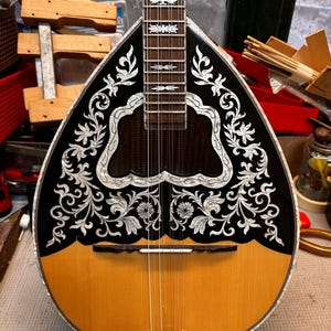 May include: A white ceramic mug with a black handle and the text "But First, Coffee" in a black, handwritten-style font. The mug is on a white surface.