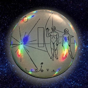 Puede incluir: Un disco circular plateado con una imagen en blanco y negro de una figura humana, una mujer y un diagrama de un sistema solar. El disco tiene un brillo iridiscente arcoíris.