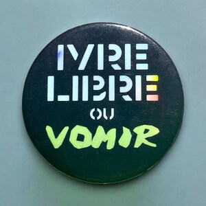 Puede incluir: Un botón negro y verde con el texto "VIRE LIBRE OU VOMIR" en blanco y verde.