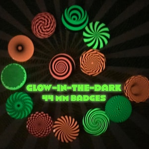 Peut inclure: Un ensemble de 10 badges phosphorescents avec différents motifs tourbillonnants en vert, orange et noir. Les badges mesurent 44 mm de diamètre et indiquent "Glow-in-the-Dark 44 mm Badges".