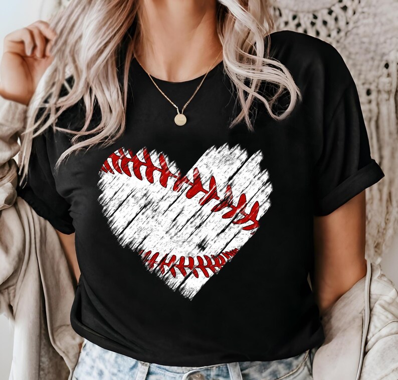 Puede incluir: Camiseta negra con un gr&aacute;fico de b&eacute;isbol en forma de coraz&oacute;n blanco. El coraz&oacute;n tiene costuras rojas y un aspecto desgastado.