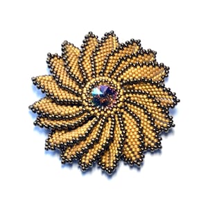Pode incluir: Um broche de flor de contas douradas e marrons com um cristal iridescente no centro.