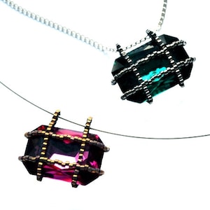 以下が含まれることがあります： ケージ付き宝石ペンダントがついたネックレスが2本。上のペンダントは、銀色のケージに入った濃い緑色の宝石。下のペンダントは、金色のケージに入ったピンク色の宝石です。