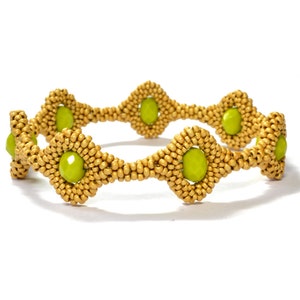 May include: A gold beaded bracelet with green gemstone accents. The bracelet is made of small, round beads and features a repeating pattern of diamond-shaped sections.
