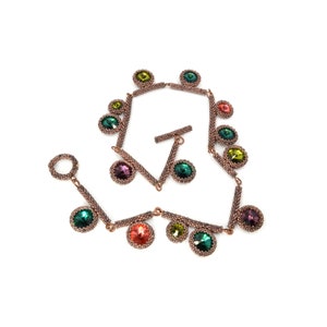 May include: A copper-toned beaded necklace with a variety of colored crystal beads. The necklace features a toggle clasp and is made with small, round beads.