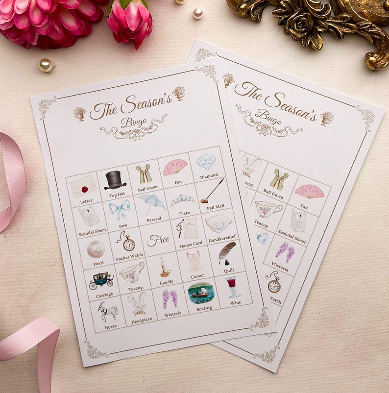 K&ouml;nnte beinhalten: Zwei wei&szlig;e Bingokarten mit dem Text "The Season's Bingo" und illustrierten Quadraten. Die Quadrate zeigen Zeichnungen eines Zylinders, eines Ballkleides, eines F&auml;chers und anderer Gegenst&auml;nde. Die Karten sind mit floralen Akzenten verziert.