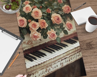 Puede incluir: Un rompecabezas rectangular que muestra un piano antiguo con pintura blanca desgastada y teclas blancas y negras. Un ramo de rosas de color melocotón suave descansa sobre el piano. El texto "even silence can be beautiful" está impreso en el piano.