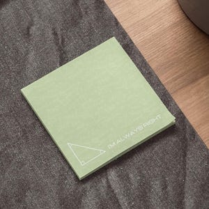 May include: A square, light green sticky note pad with a white right triangle graphic and the text "I'M ALWAYS RIGHT". The pad is covered in faint mathematical equations.
