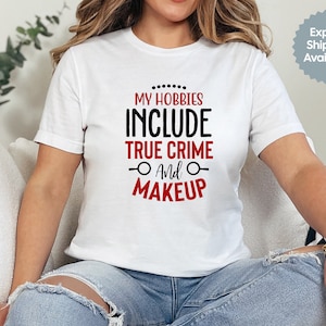Pode incluir: Camiseta branca com texto preto que diz "Meus hobbies incluem crime verdadeiro e maquiagem" em vermelho.