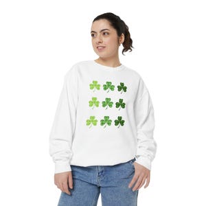 May include: White sweatshirt with a green shamrock pattern. The shamrocks are arranged in a grid pattern.