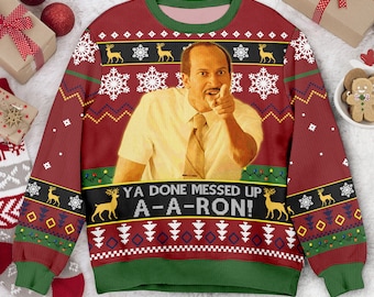 May include: A red long-sleeve crewneck sweatshirt with green trim featuring a photographic print of a man in a white shirt and tie pointing forward. The text reads YA DONE MESSED UP A-A-RON! surrounded by patterns of snowflakes, reindeer, and trees.