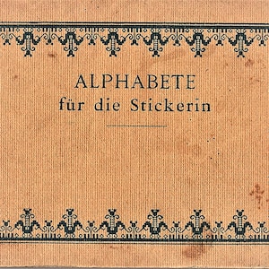 Puede incluir: Una portada de libro vintage con el título "ALPHABETE für die Stickerin" en fuente negra. La portada tiene un fondo beige con un borde negro decorativo. El libro parece ser una guía para el bordado.