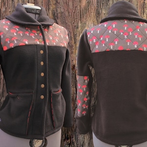 May include: A black fleece jacket with a brown and red mushroom pattern on the back and sleeves. The jacket has a collar, a button closure, and two pockets.