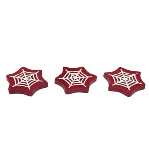 May include: Three red star-shaped coasters with a white spiderweb design.