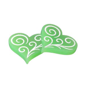 Puede incluir: Dos adornos verdes en forma de corazón con patrones de remolinos blancos. Los corazones se superponen ligeramente. El diseño es simple y elegante, adecuado para diversos fines decorativos. Los corazones miden unos 3 cm de ancho.