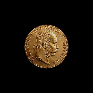 Può includere: Una moneta d'oro con il profilo di un uomo con barba e corona d'alloro. La moneta ha un testo attorno al bordo ed è ambientata su uno sfondo nero. La moneta sembra essere antica.