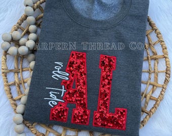 May include: A dark gray crewneck sweatshirt featuring the text "HARPERN THREAD CO." at the top. The front displays the letters "AL" in large, red, sequined block font, with the white cursive text "roll Tide" positioned to the left of the letters.