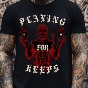 May include: Black t-shirt with a red devil graphic holding two billiard balls. The text "PLAYING FOR KEEPS" is written in white gothic lettering.