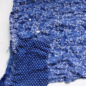 May include: A blue fabric with a white floral pattern. The fabric has a patch sewn on it with a smaller white dot pattern.